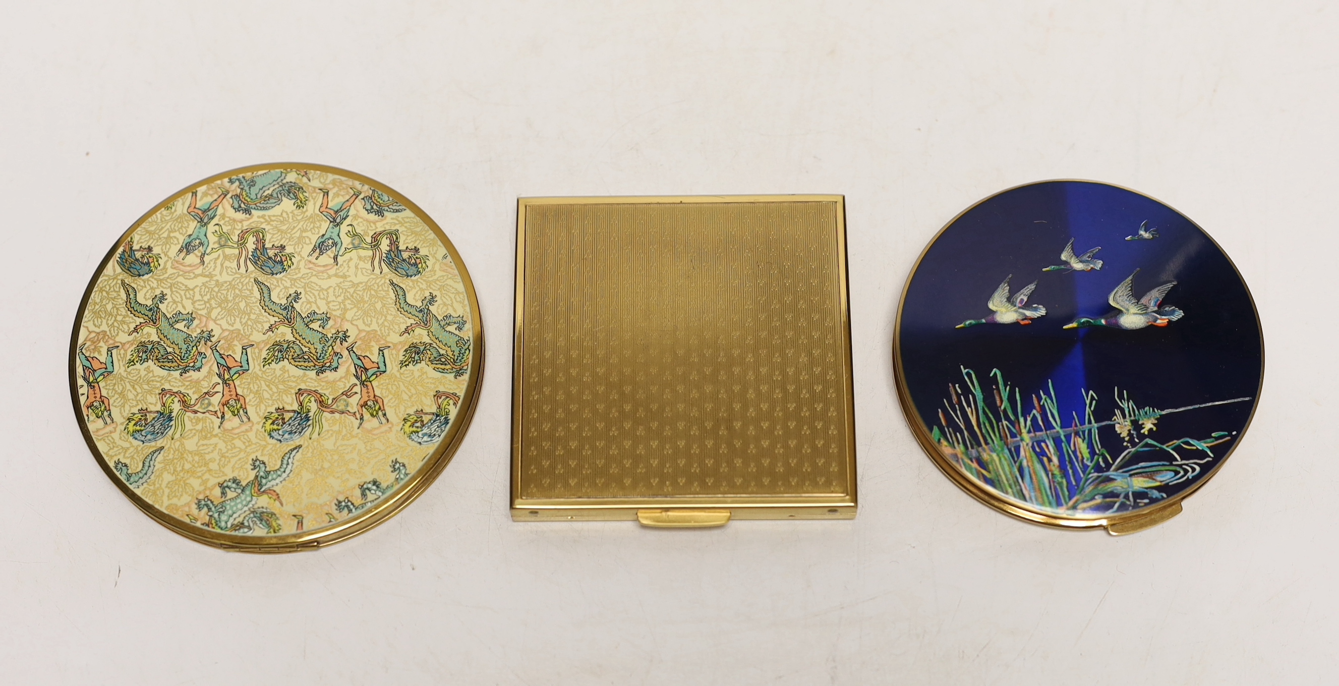 Three compact mirrors, collection consisting of an example of one each of a Stratton Flying Ducks, King K&K Sunburst and Vanities Dragon design.